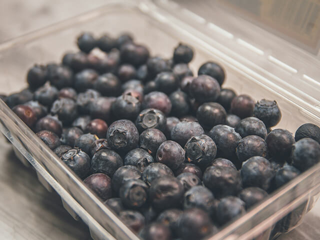 Food-grade weighing machine with berries in industrial packaging tray