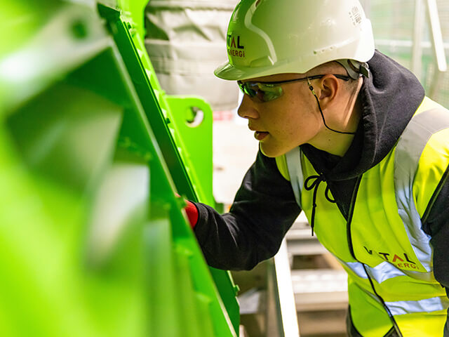 Field technician inspecting industrial equipment wearing safety gear